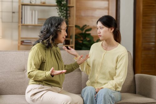 mature mom and adult daughter have fight at home while sitting on sofa