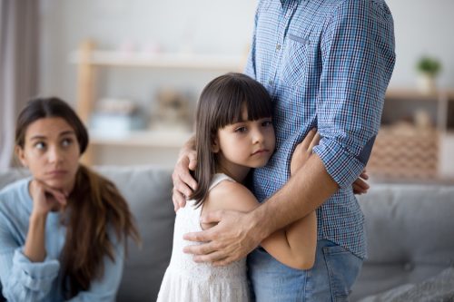 sad kid showing her father affection but ignoring her mother