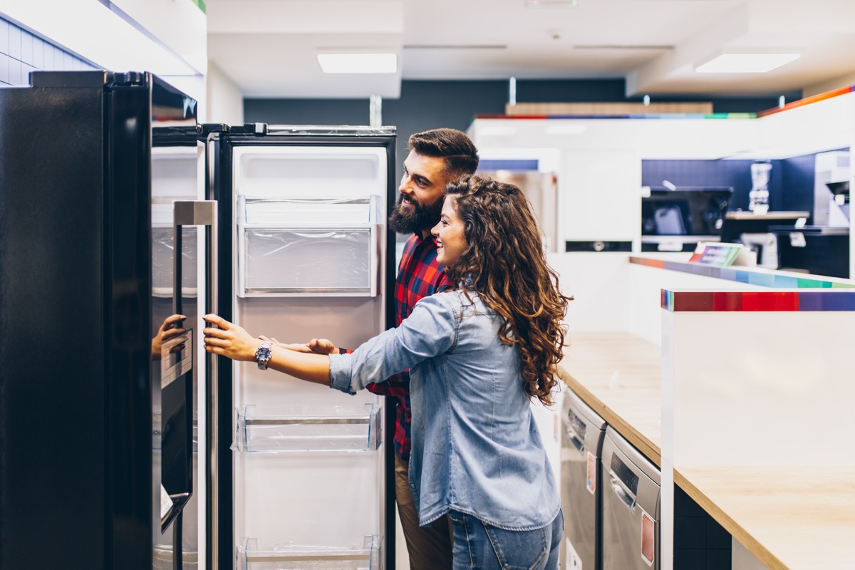 Young couple, satisfied customers choosing fridges in appliances store.