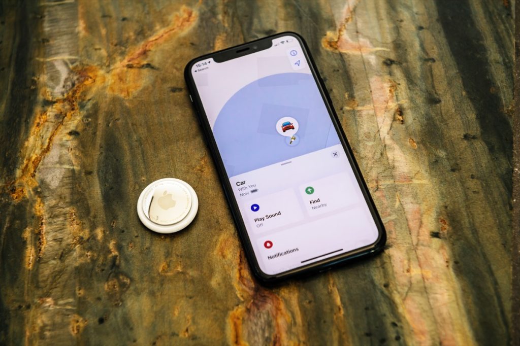 Airtag sitting next to smartphone with Find My app on screen