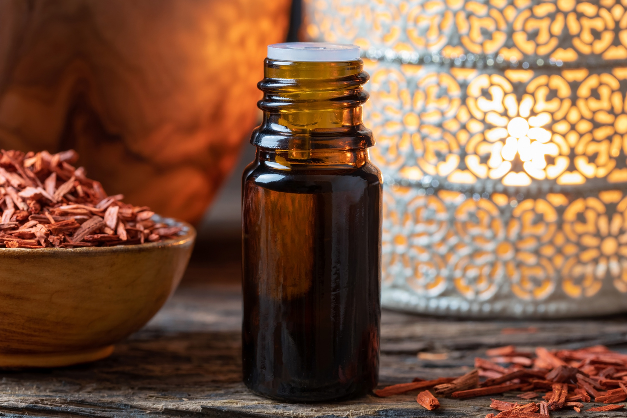 A bottle of sandalwood essential oil with red sandalwood chips