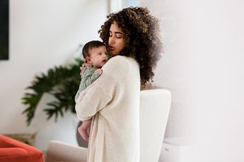 woman in white sweater holding newborn baby