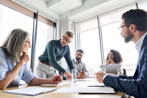 boss leading a work meeting at a board table