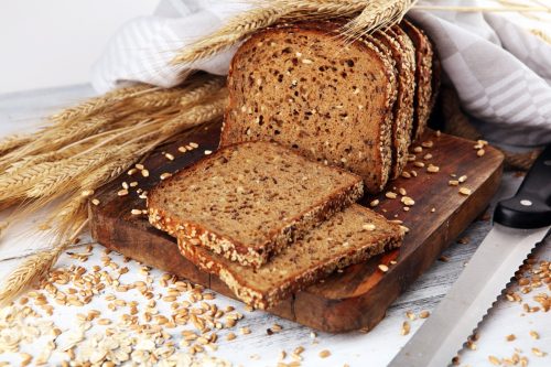 Sliced rye bread on cutting board. Whole grain rye bread with seeds on rustic background