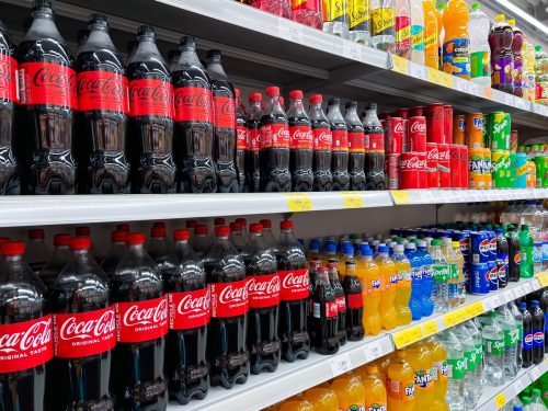 Coca-cola bottles on row display for sale in supermarket shelf, Riga. Latvia. Coca-Cola Company is the leading producer of carbonated beverages in the world.