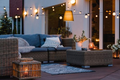 Summer evening on the patio of beautiful suburban house with lights in the garden garden