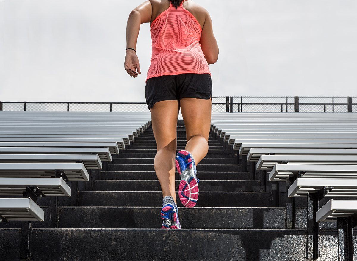 rear view of a woman running up outdoor bleachers