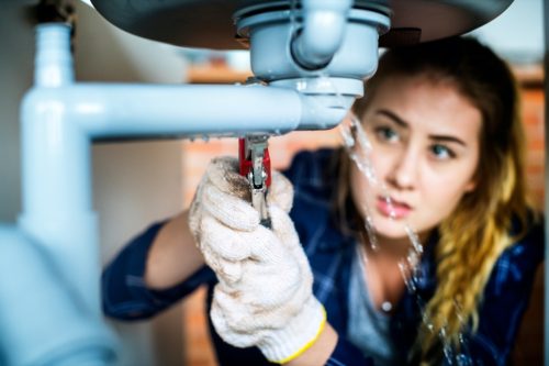 young woman fixing leaking pipe