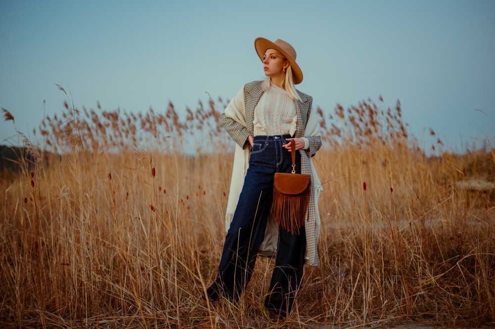 Fashionable, stylish woman wearing wide leg jeans, scarf, and hat