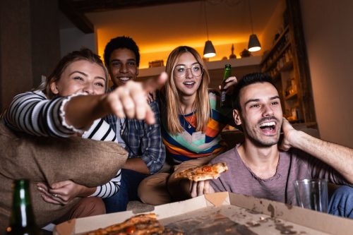 people watching a TV screen with pizza