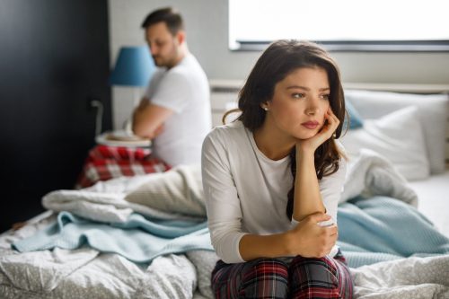 Sad couple sitting on bed after having a quarrel