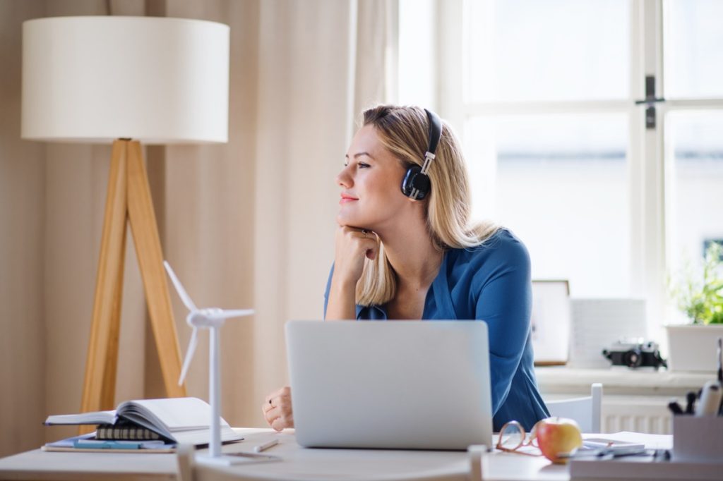 woman looking peaceful while she works at her desk with headphones on and a laptop in front of her