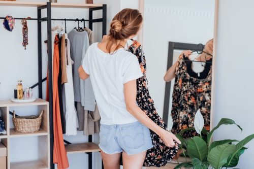 Blonde young woman choosing clothes on clothes rack dressing looking herself in mirror. Girl think what to wear. Lifestyle women. Turkey, 29.05.2022