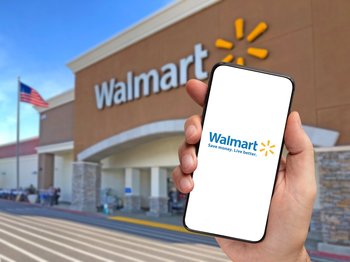 Ứng dụng giao hàng của nhà bán lẻ Walmart trên điện thoại thông minh cầm trên tay với cửa hàng Walmart mờ ở phía sau