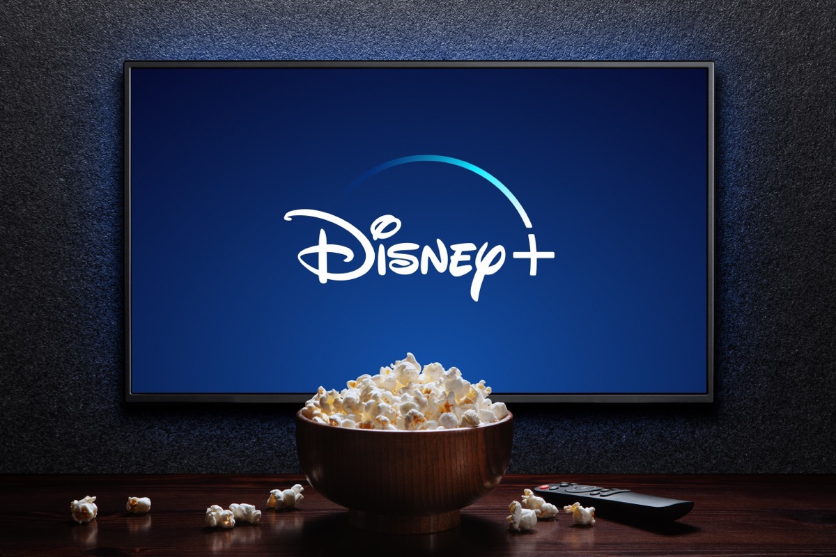 Logo Disney Plus trên TV với bát đựng bỏng ngô và điều khiển từ xa trên bàn. Disney Plus là dịch vụ phát trực tuyến video theo đăng ký của Mỹ. Astana, Kazakhstan - Ngày 21 tháng 7 năm 2023.