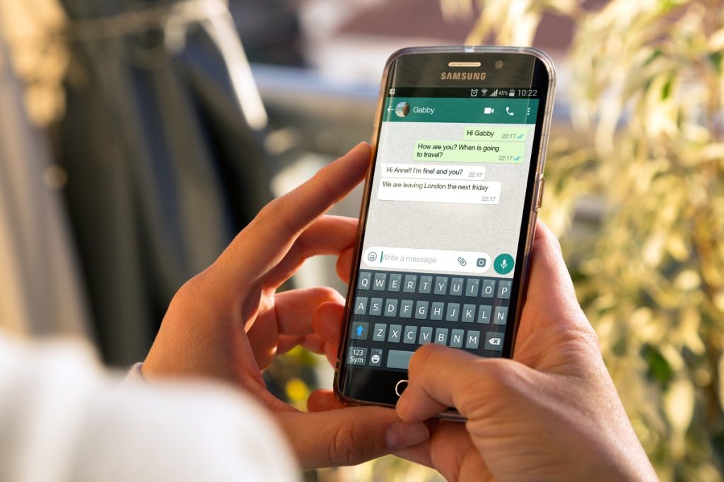 A woman with a smartphone in her hands and a whatsapp conversation on the screen.