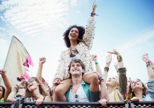 woman on man's shoulders at music concert