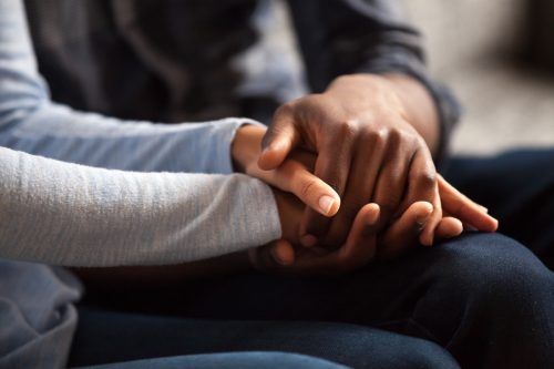 Interracial couple holding hands during an apology