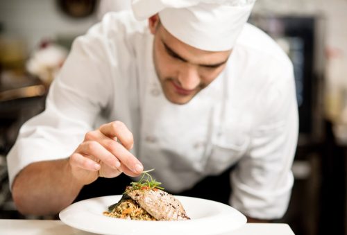 Male chef garnishing dish dish