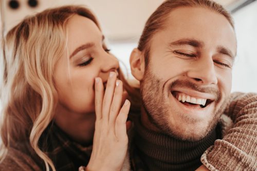 white woman whispering to laughing white man