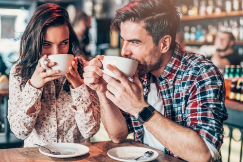 young couple drinking coffee and looking at each other while flirting