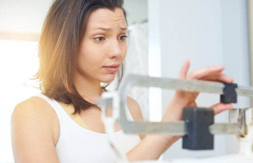 Woman schecking the scale with a concerned look on her face