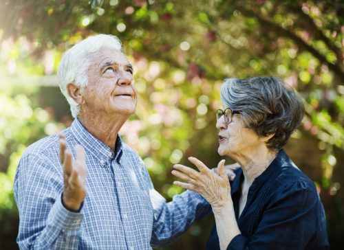 A senior man rolls his eyes, frustrated, as his partner gestures at him angrily.