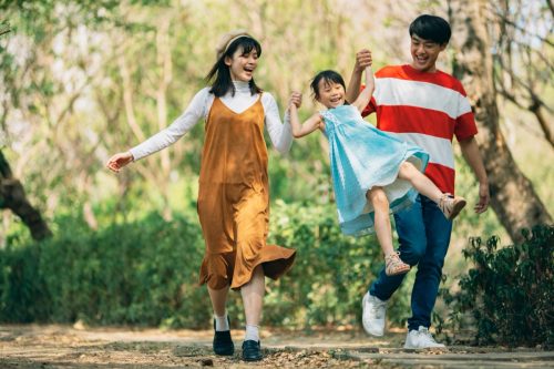 An Asian family of three heads to the park for a picnic, indulging in games and blowing bubbles together.