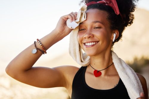 Smile, sweat and black woman on street after workout, training and exercise for wellness, peace or health outdoor. Music, radio and gen z girl walking by nature, environment and park with happiness