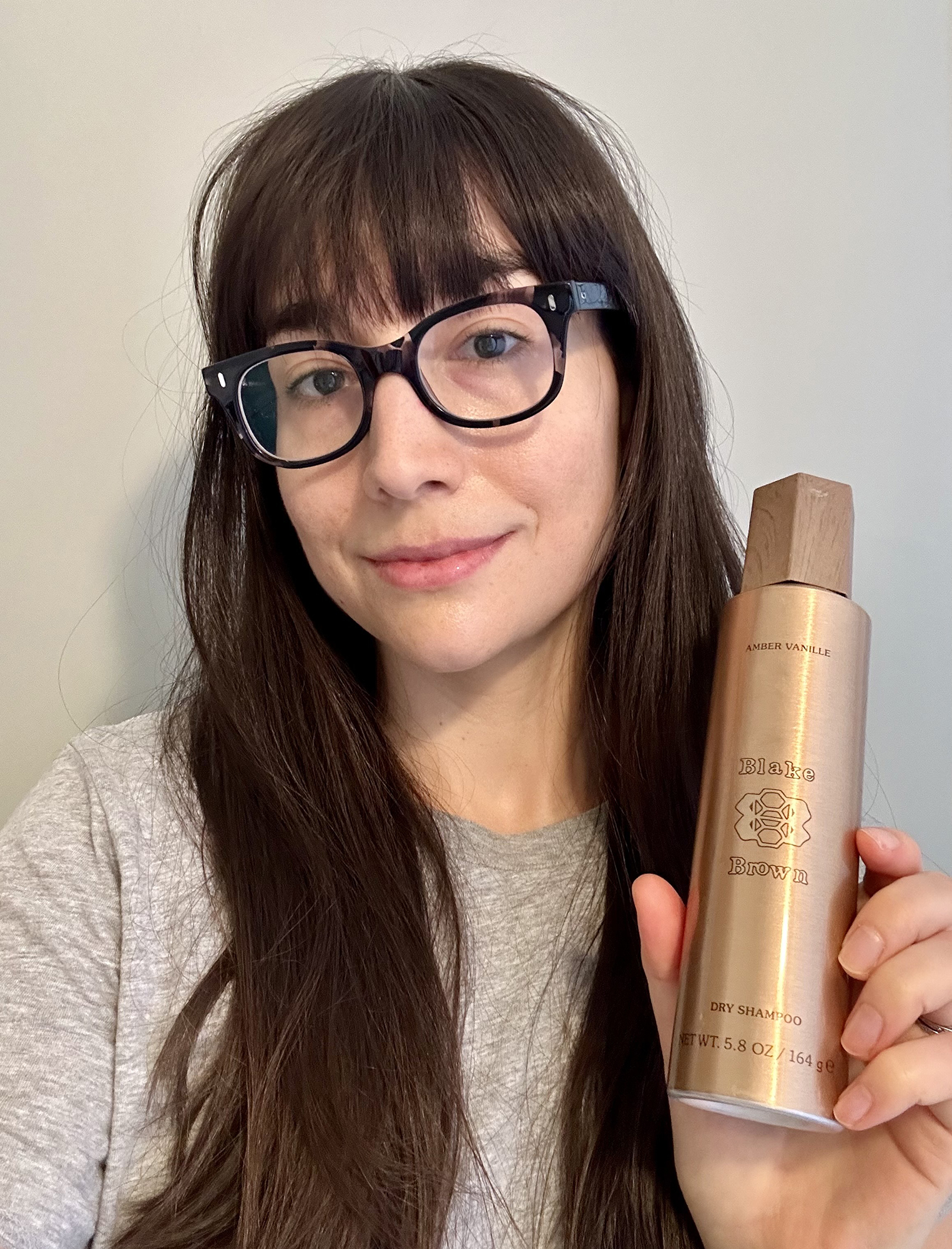 Elana Fishman holding a bottle of Blake Brown Amber Vanille Dry Shampoo