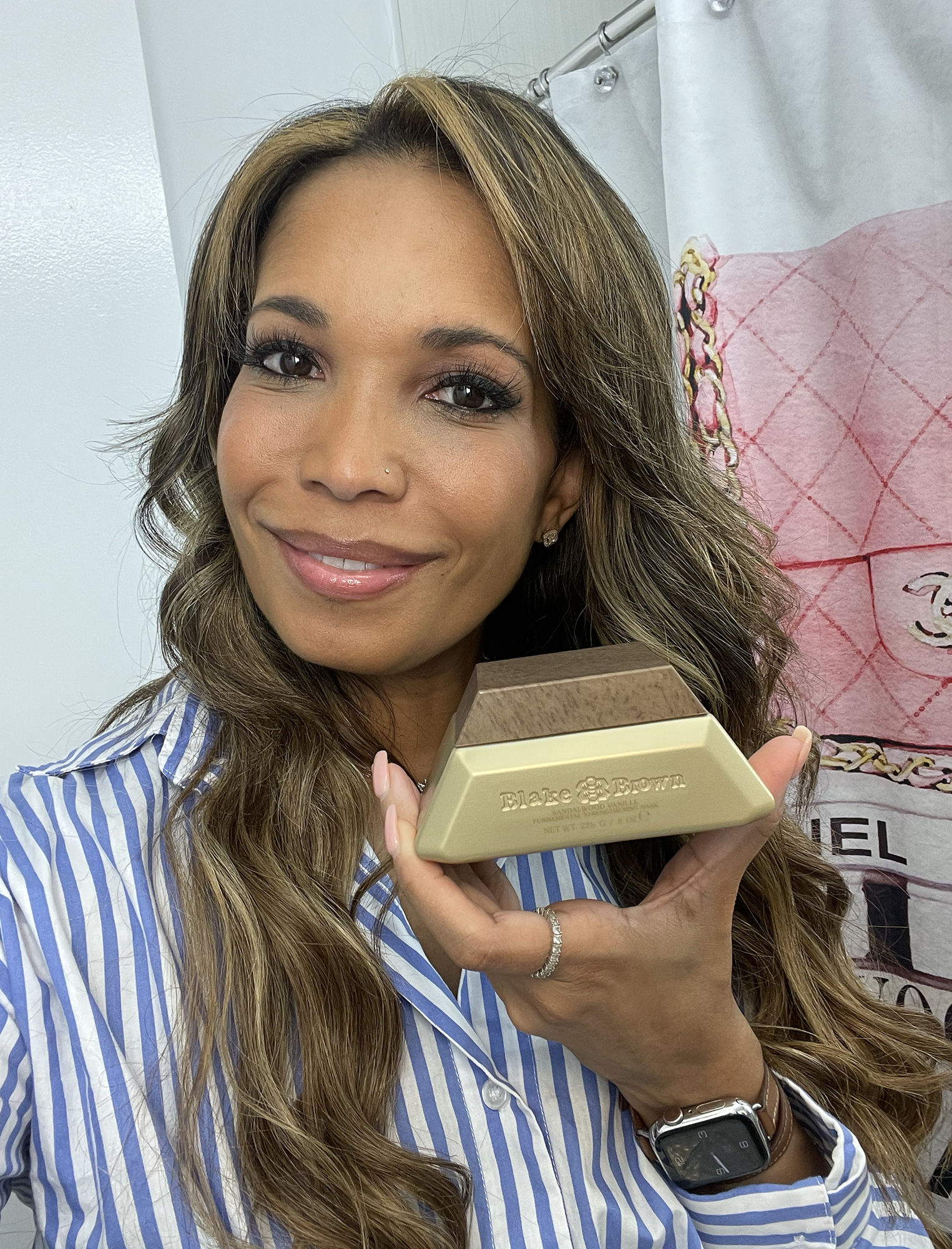 Astra holding a bottle of Blake Brown Sandalwood Vanille Fundamental Strengthening Mask