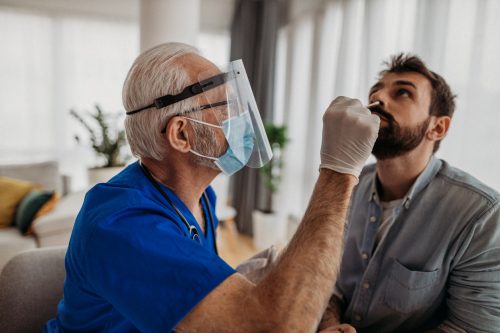 A young man getting a nasal swab from a healthcare worker as part of a COVID-19 test