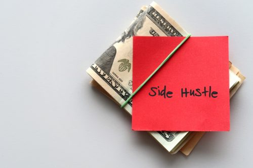 Tiền mặt đô la và tờ giấy ghi chữ SIDE HUSTLE ở nền - khái niệm về lập kế hoạch tài chính - kiếm thêm tiền từ công việc phụ bán thời gian hoặc công việc thứ hai