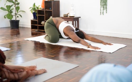 Yoga teacher in childs pose in front of class